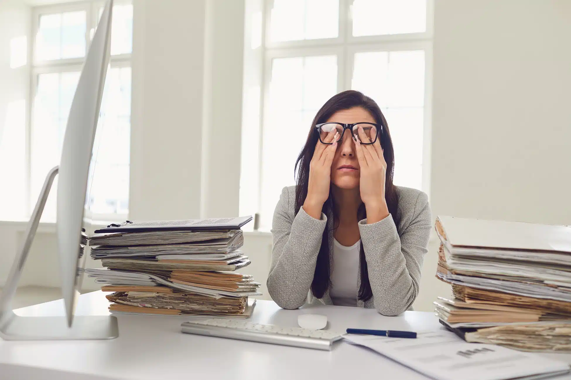 A Guide to Short-term Disability for Burnout 1 Overwhelmed professional woman rubbing eyes surrounded by stacks of paperwork