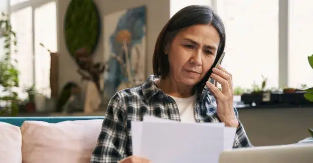 A person reading paperwork while on the phone