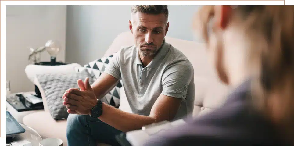 A man sits on his couch, discussing his disability case with an attorney.