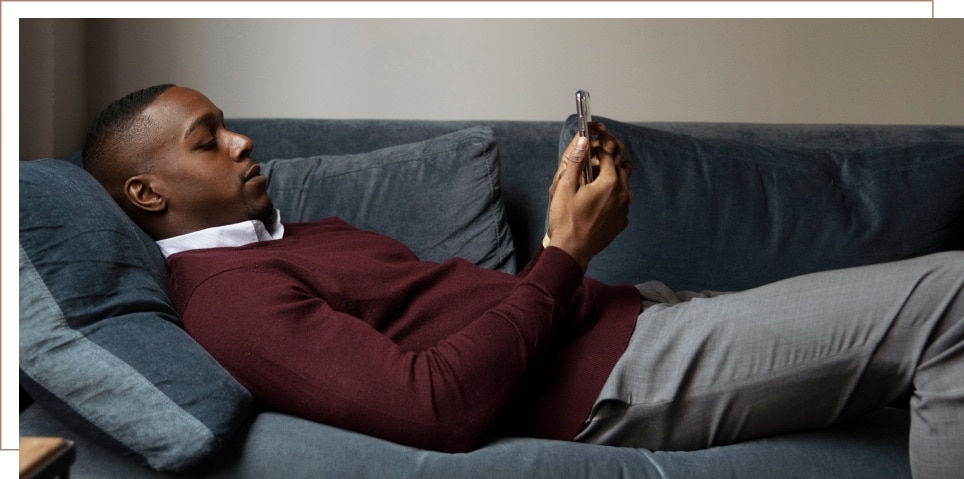 A man on a couch reading on his cell phone