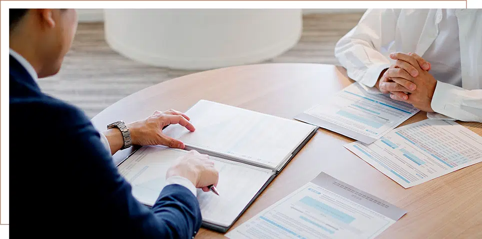 Long-Term Disability Benefits 5 Attorney reviewing paperwork with a client at a round table, discussing documents spread out in a professional office environment.