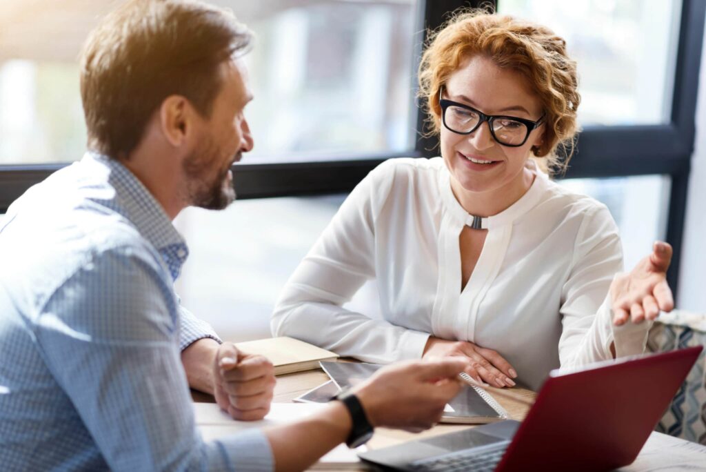 Attorney and client engaged in a professional legal consultation at an office desk with laptop and documents