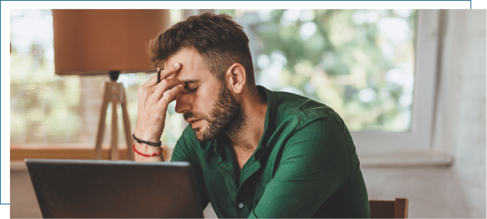 A man looking frustrated and exhausted sitting with his head in his hand