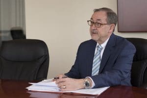 Professional male attorney in navy suit seated at desk reviewing legal documents in office setting