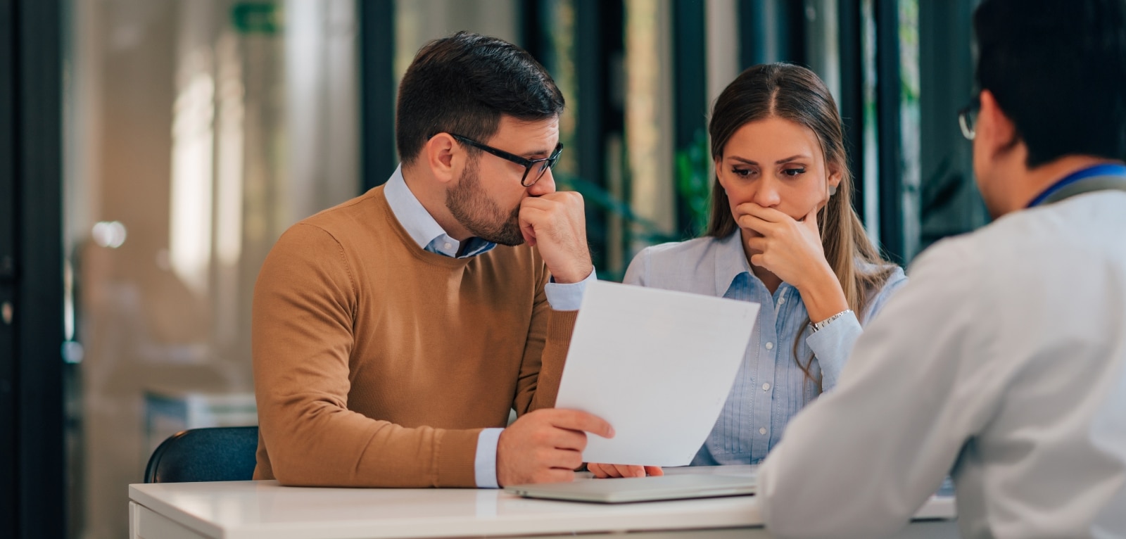 Concerned couple reviewing legal documents with an attorney during a consultation meeting in a law office