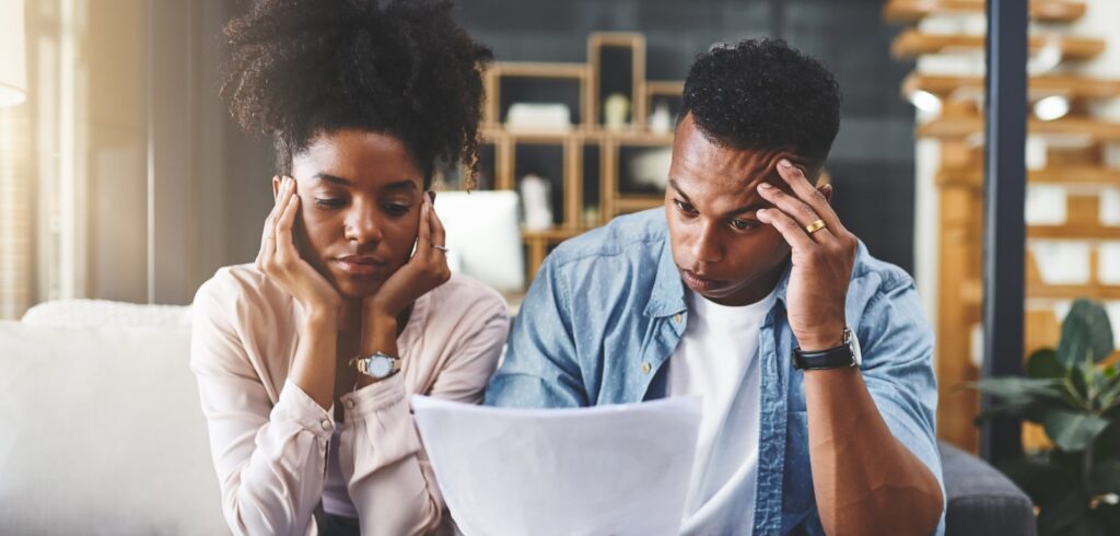 Concerned couple reviewing legal documents together at home, both appearing stressed and troubled by the contents