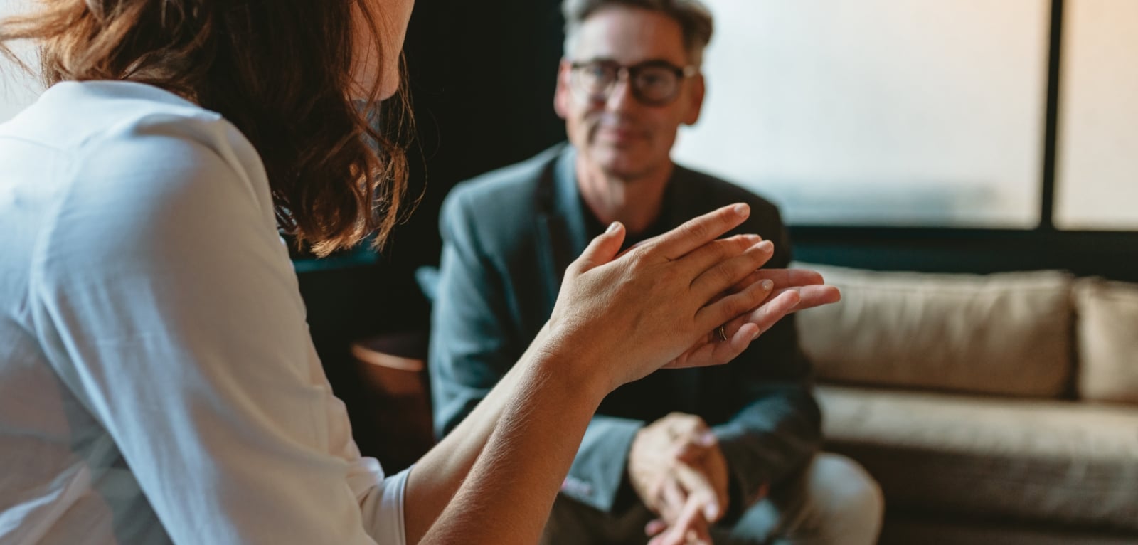 A woman gesturing with her hands during a conversation with a male attorney in a professional office setting