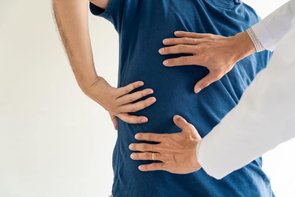 Doctor examining a patient's lower back pain during a medical consultation