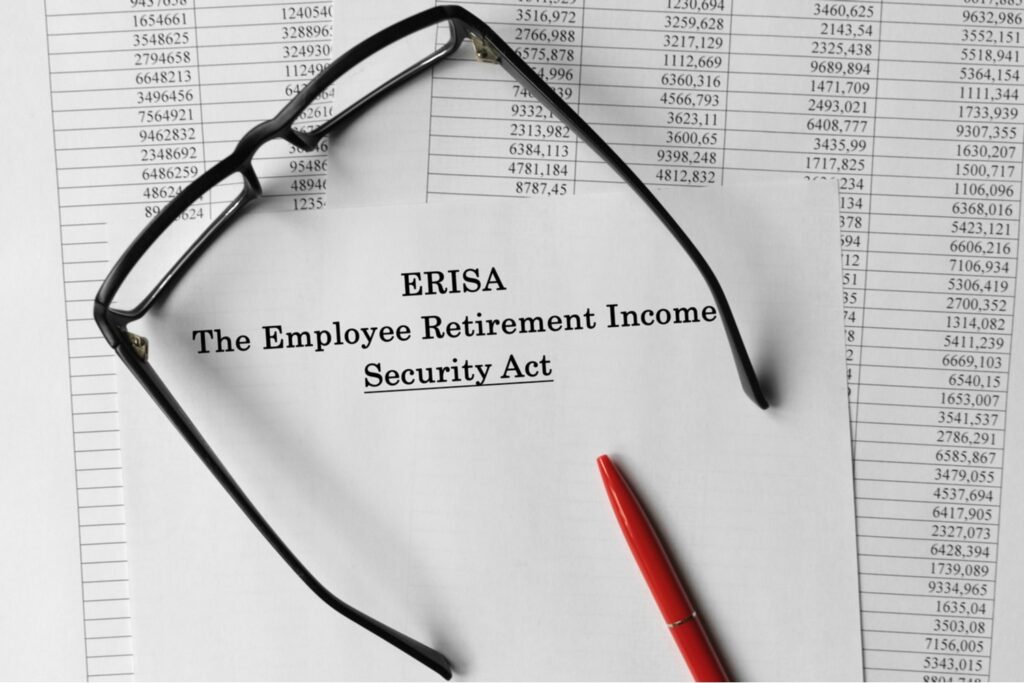 ERISA Employee Retirement Income Security Act document with reading glasses and red pen on financial data spreadsheets