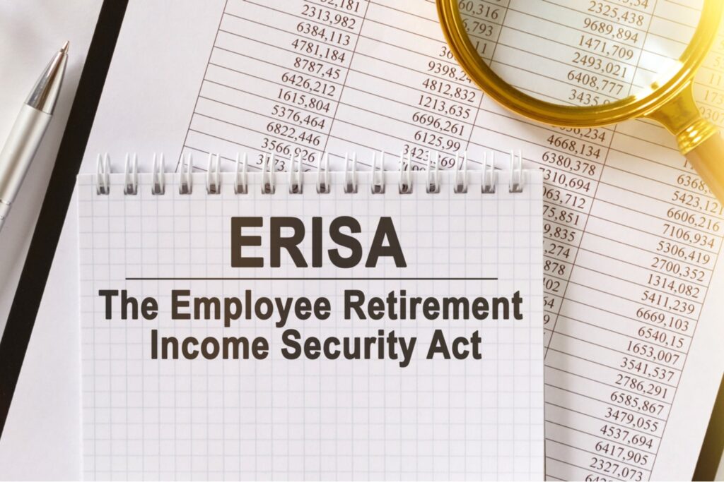 Notepad labeled "ERISA – The Employee Retirement Income Security Act" beside financial documents, a pen, and a magnifying glass