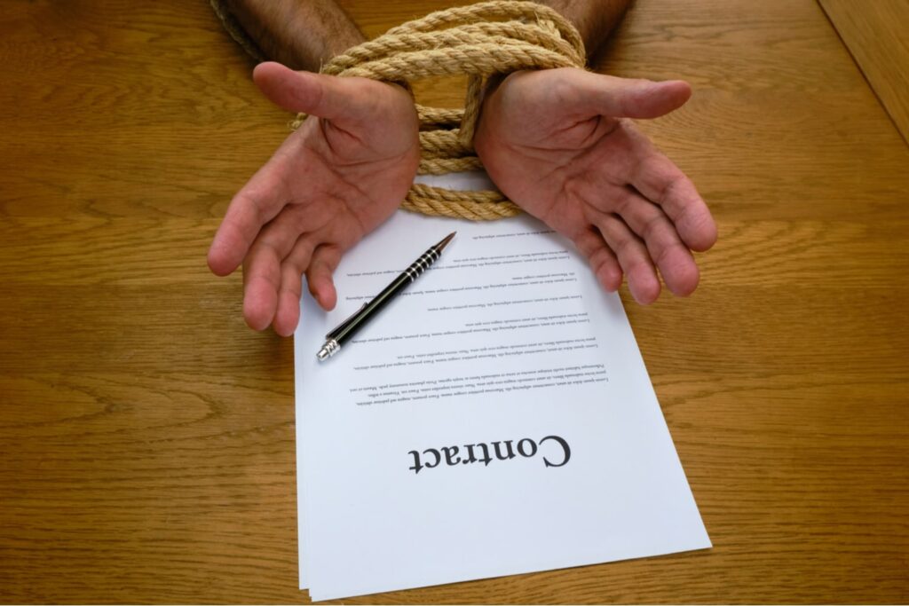 Hands bound together with rope over a contract document and pen, symbolizing coercion or unfair contractual obligations