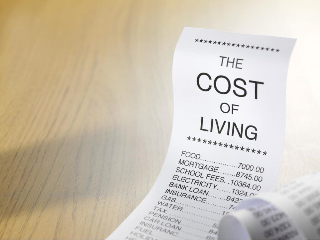 Receipt listing cost of living expenses including food, mortgage, school fees, electricity, and insurance on a wooden surface