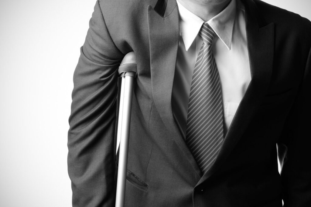 Man in a business suit using a crutch, representing a personal injury client seeking legal representation