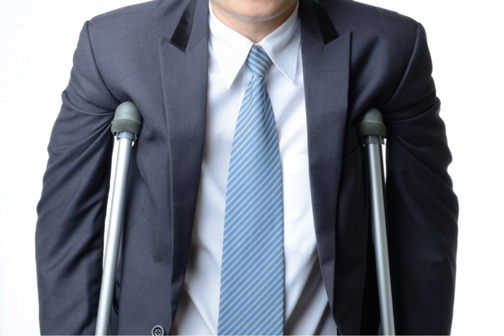 Man in a business suit and blue tie using forearm crutches, representing a personal injury or disability legal case