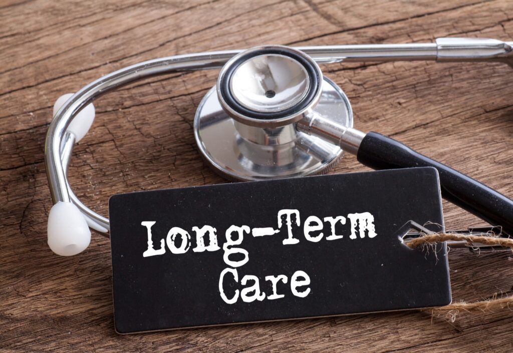 Black tag reading "Long-Term Care" beside a stethoscope on a rustic wooden surface