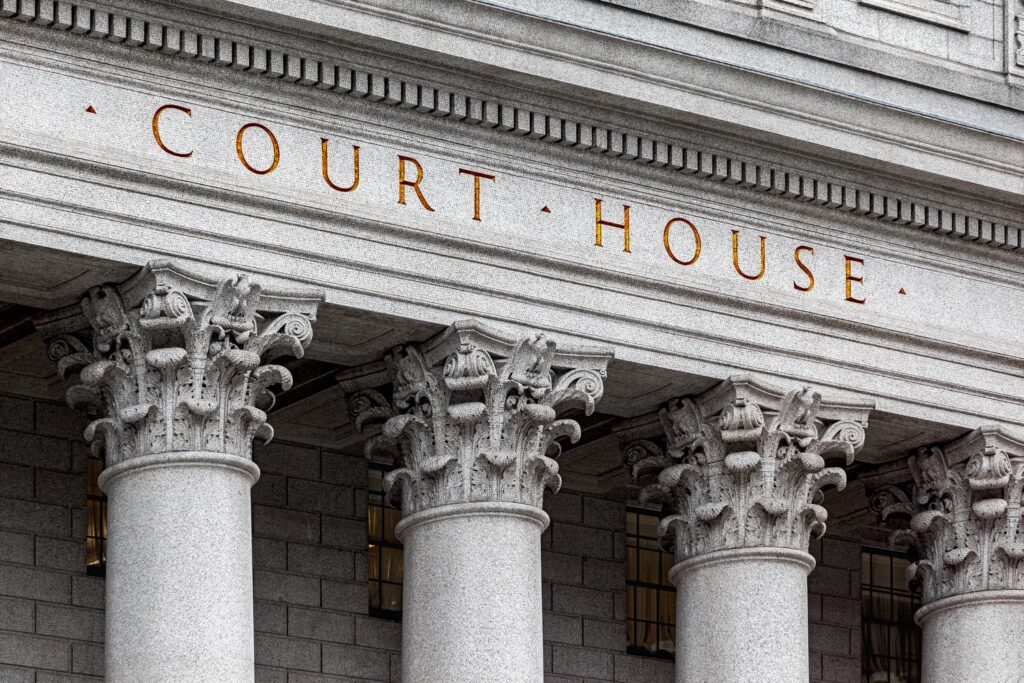 Courthouse facade with ornate Corinthian columns and gold-lettered "Court House" inscription on a stone entablature