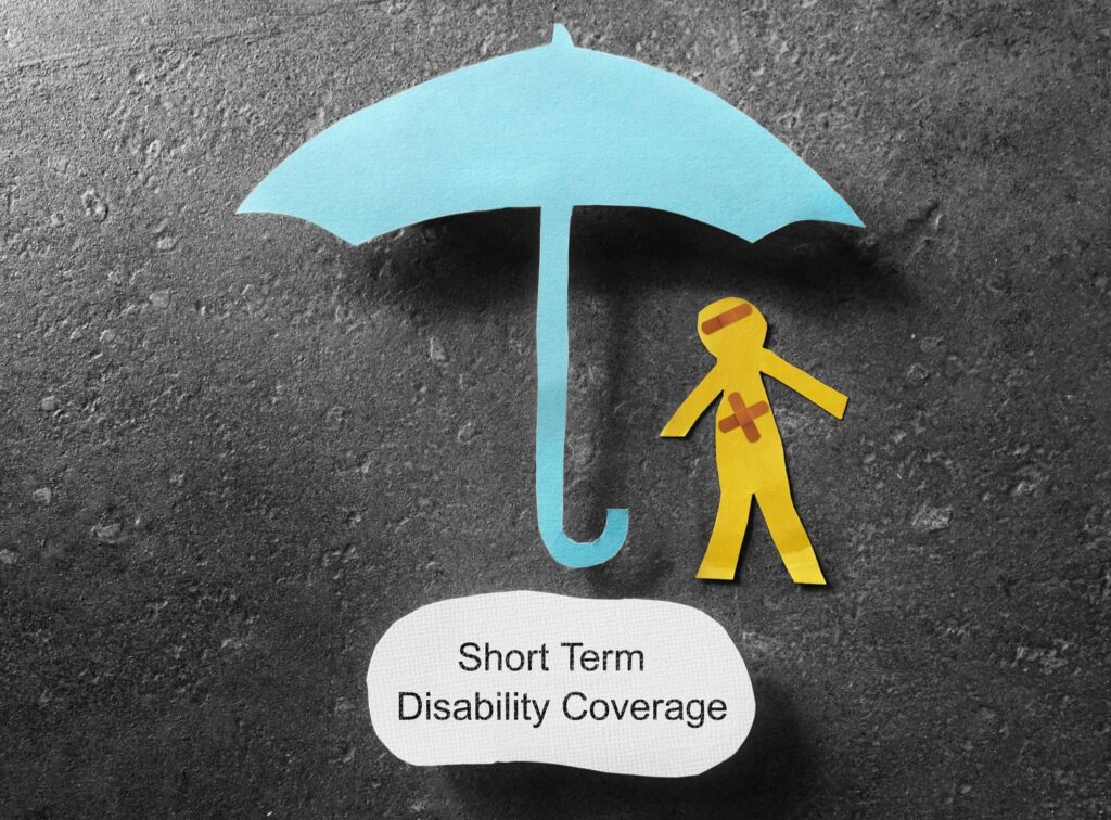 Paper cutout of injured figure with bandages under blue umbrella labeled Short Term Disability Coverage on gray background