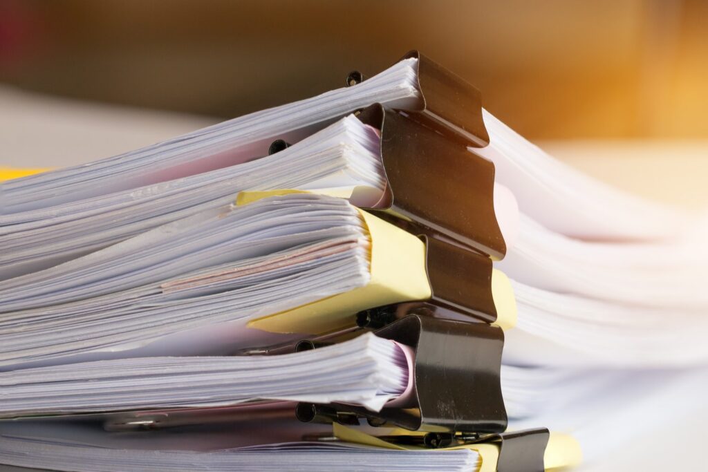 Stacked legal document files secured with binder clips on a desk, representing organized case paperwork