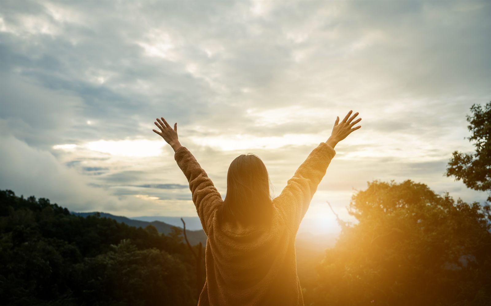 Person raising their arms at sunset after recovering with the help of short-term disability benefits