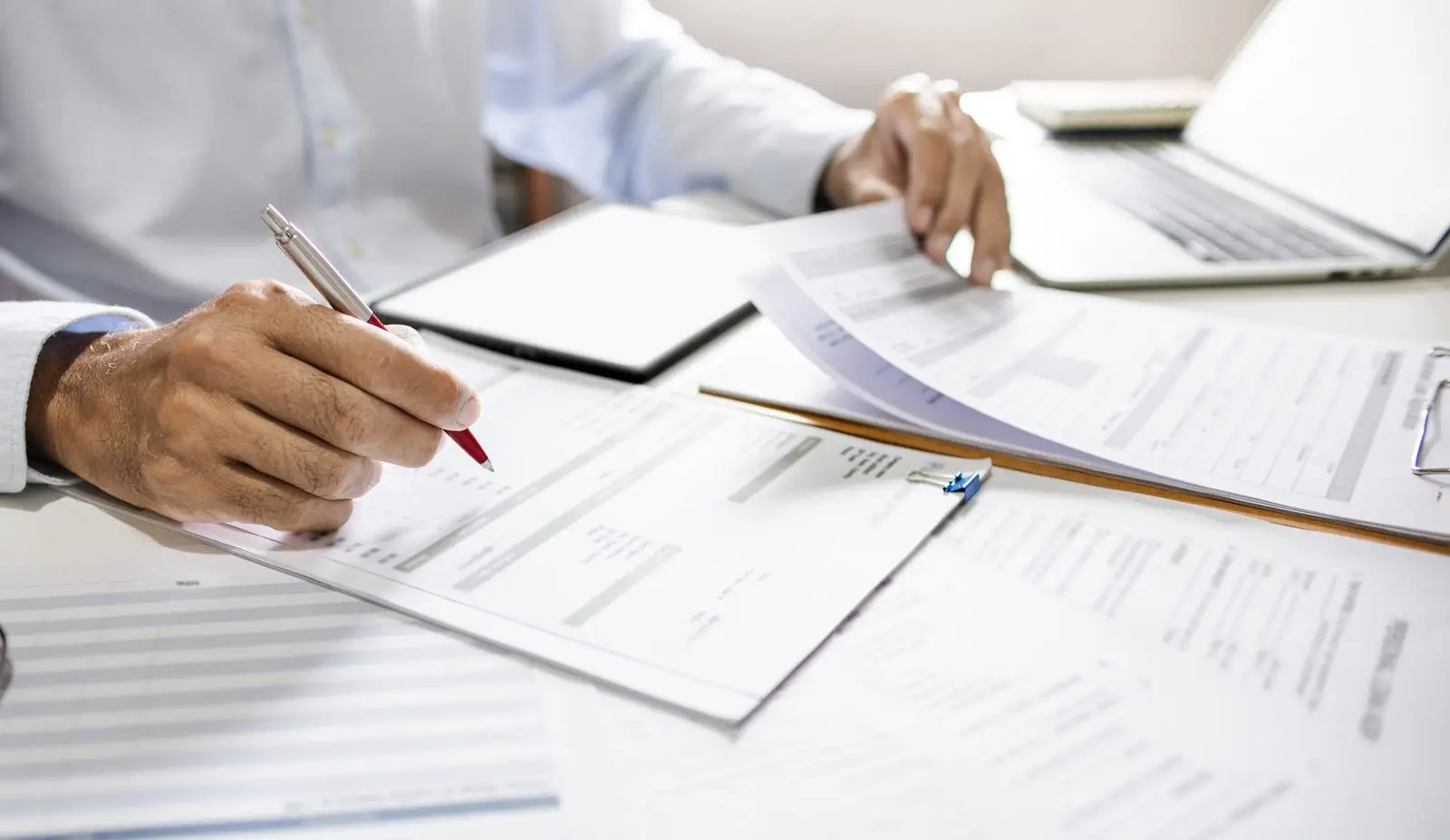 Person reviewing long-term disability policy documents and claim forms at a desk
